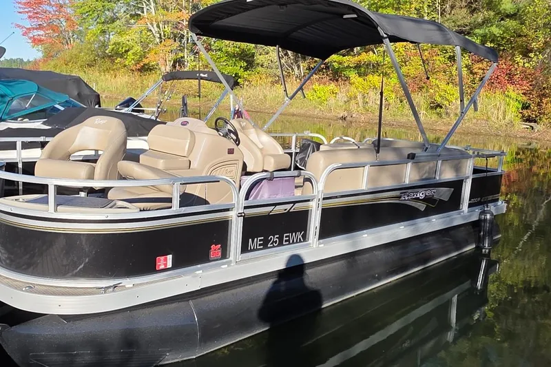 Slide: The Image of 2023 Ranger Reata 200F pontoon boat on a calm lake with autumn foliage. - 2