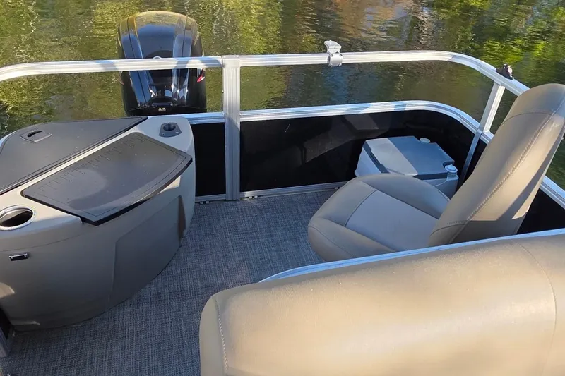 Slide: The Image of 2023 Ranger Reata 200F boat interior with seating and motor, on calm water. - 9