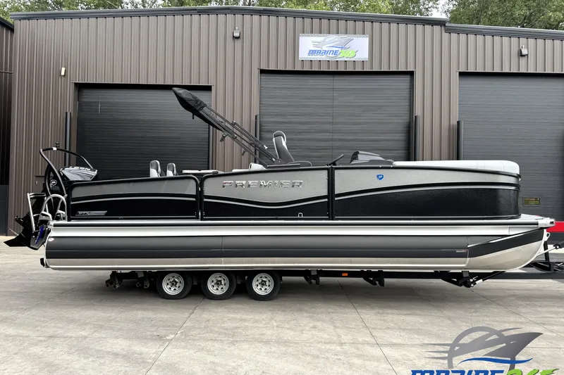 The Image of 2026 Premier 230 Solaris RS pontoon boat on trailer, parked outside a building. - 0