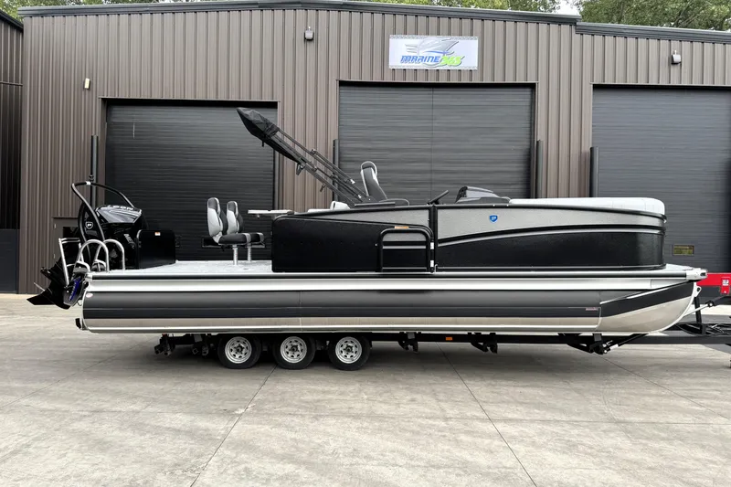 Slide: The Image of 2026 Premier 230 SOLARIS RS pontoon boat on trailer, parked outside a warehouse. - 3