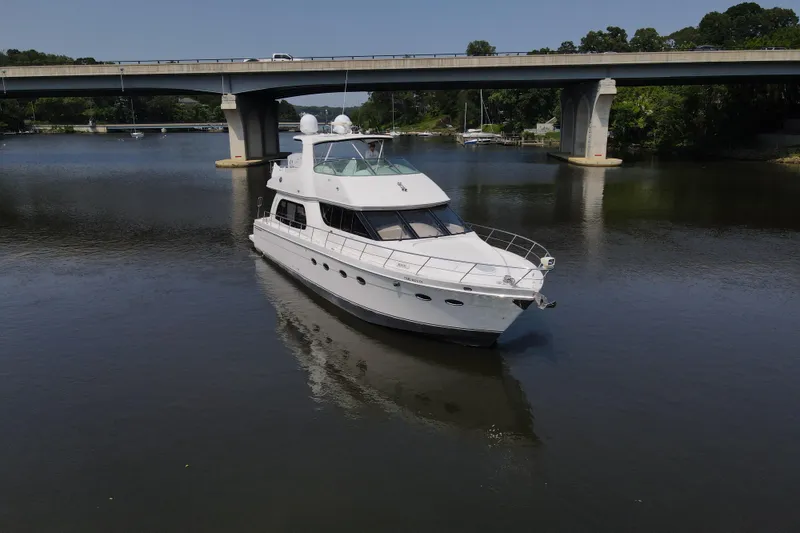 Slide: The Image of 2006 Carver 56 Voyager yacht cruising under a bridge on a calm river. - 2