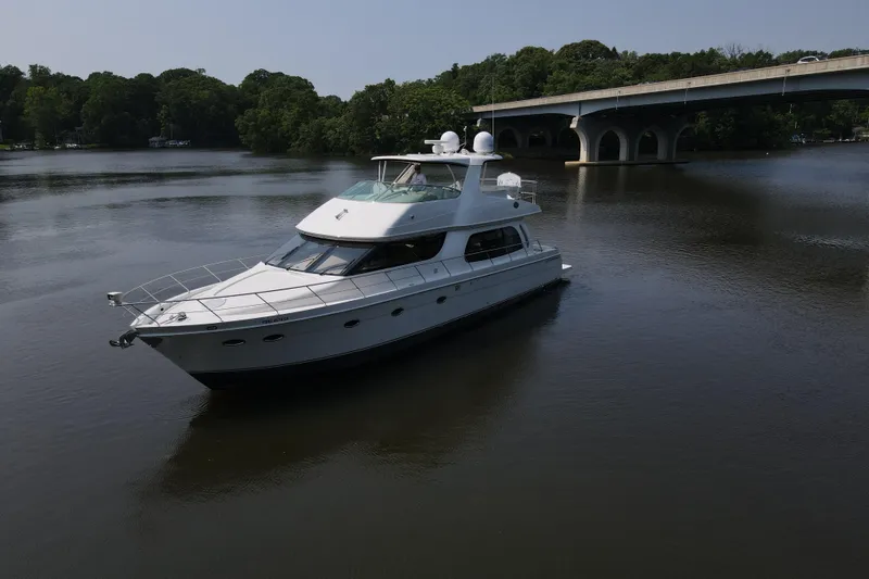 Slide: The Image of 2006 Carver 56 Voyager yacht cruising on a serene river near a bridge. - 4