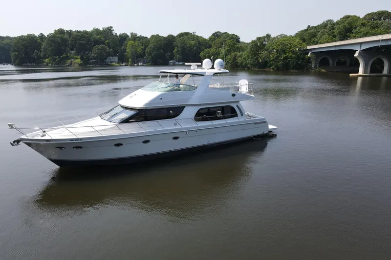 Slide: The Image of 2006 Carver 56 Voyager yacht on calm river near bridge and lush greenery. - 5