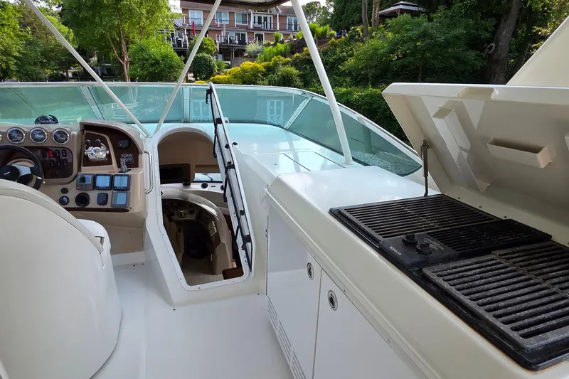 Slide: The Image of 2006 Carver 56 Voyager yacht helm with grill, surrounded by lush greenery. - 59