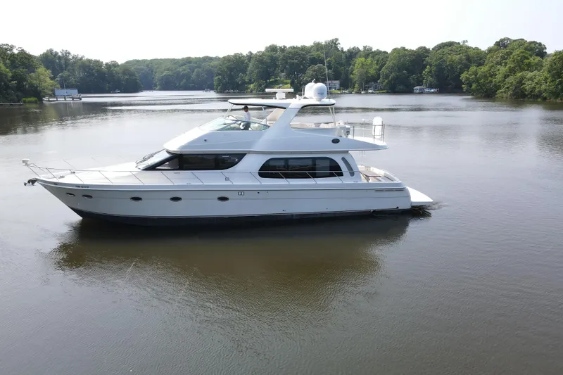 Slide: The Image of 2006 Carver 56 Voyager yacht on a serene lake with lush green surroundings. - 6
