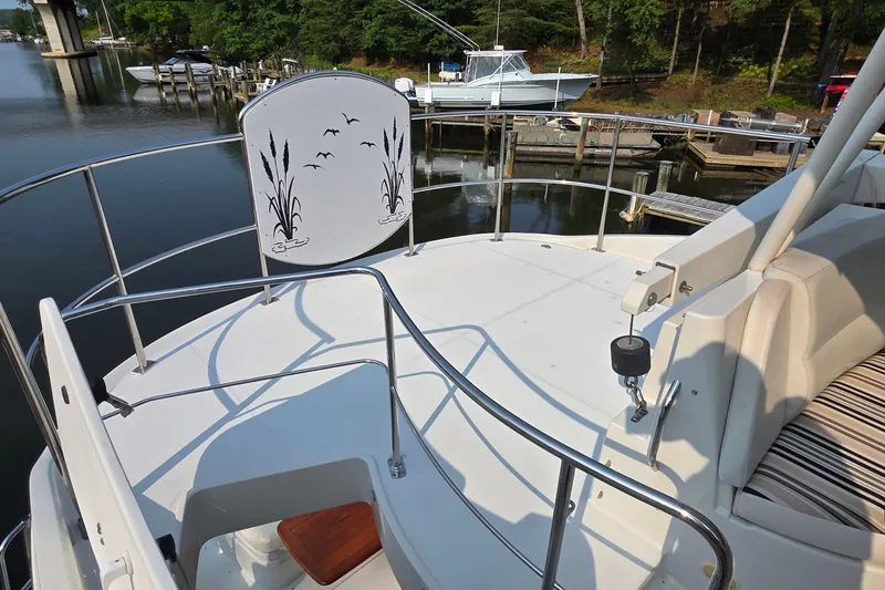 Slide: The Image of 2006 Carver 56 Voyager yacht deck with railing, docked near serene waters and lush greenery. - 67