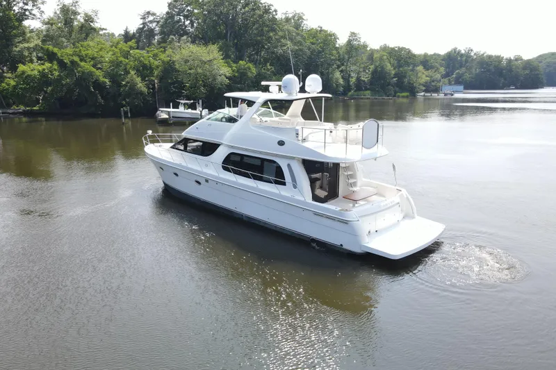 Slide: The Image of 2006 Carver 56 Voyager yacht cruising on a serene river with lush greenery. - 7