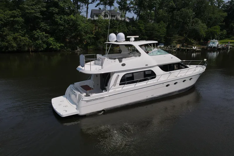 Slide: The Image of 2006 Carver 56 Voyager yacht on a serene river, surrounded by lush greenery. - 9