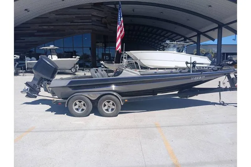 Slide: The Image of 1994 Gambler 21 boat on trailer, parked outdoors with American flag in background. - 1