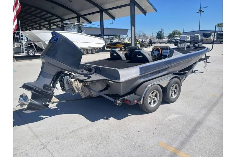 Slide: The Image of 1994 Gambler 21 boat on trailer, parked outdoors under a canopy. - 2