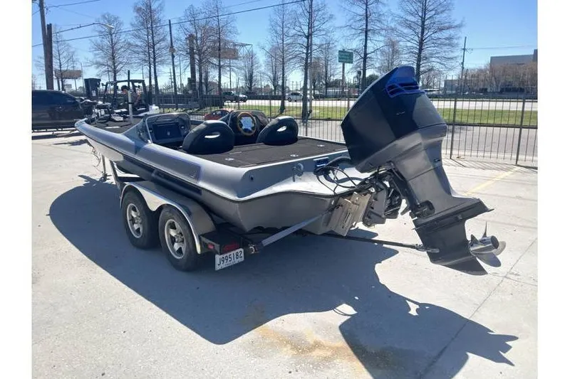 Slide: The Image of 1994 Gambler 21 boat with outboard motor on a trailer in a parking lot. - 3