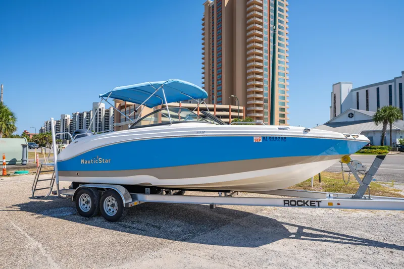 Slide: The Image of 2017 NauticStar 223DC Sport Deck boat on trailer, urban background, clear sky. - 0