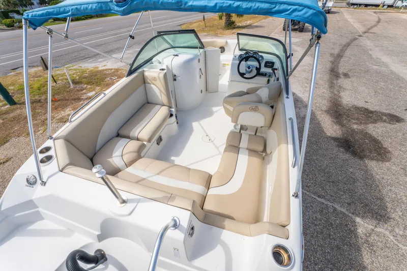 Slide: The Image of 2017 NauticStar 223DC Sport Deck boat with beige seating and blue canopy. - 10