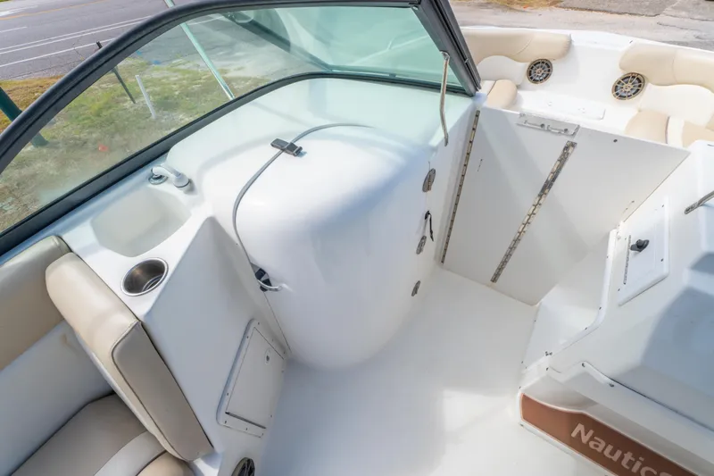 Slide: The Image of 2017 NauticStar 223DC Sport Deck interior with seating, cup holder, and open storage compartment. - 17