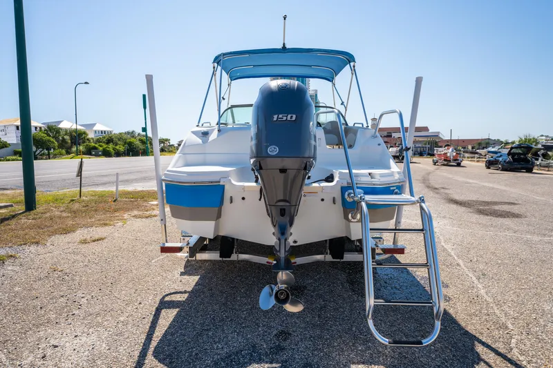 Slide: The Image of 2017 NauticStar 223DC Sport Deck boat with outboard motor and ladder, parked on a sunny day. - 5