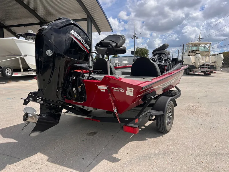 Slide: The Image of 2024 Tracker Pro Team 175 boat with Mercury engine, parked outdoors under cloudy sky. - 4