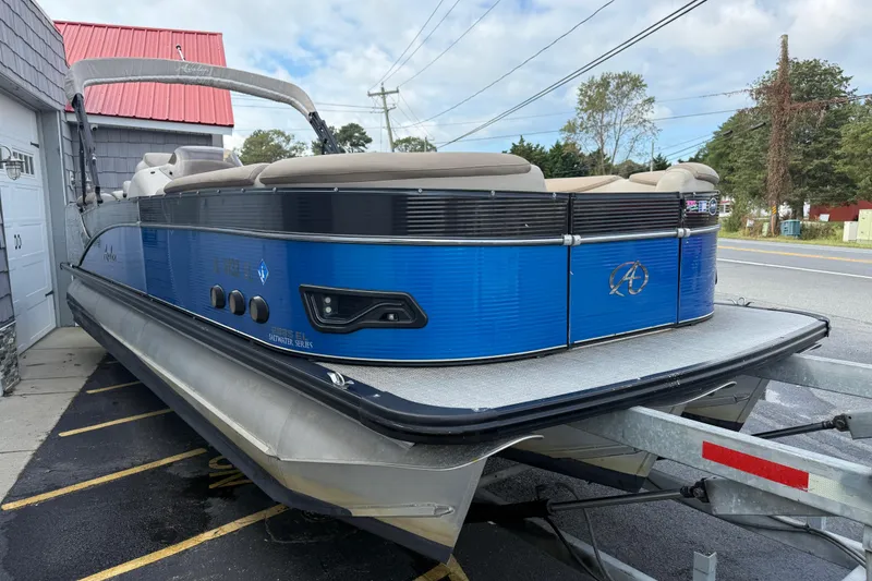 Slide: The Image of 2018 Avalon 2585 Catalina Elite Tri-toon boat on trailer, blue exterior, parked outdoors. - 10