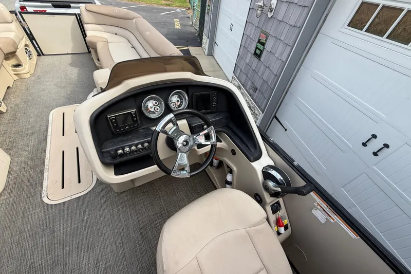 Slide: The Image of 2018 Avalon 2585 Catalina Elite Tri-toon boat interior with steering console and seating. - 22
