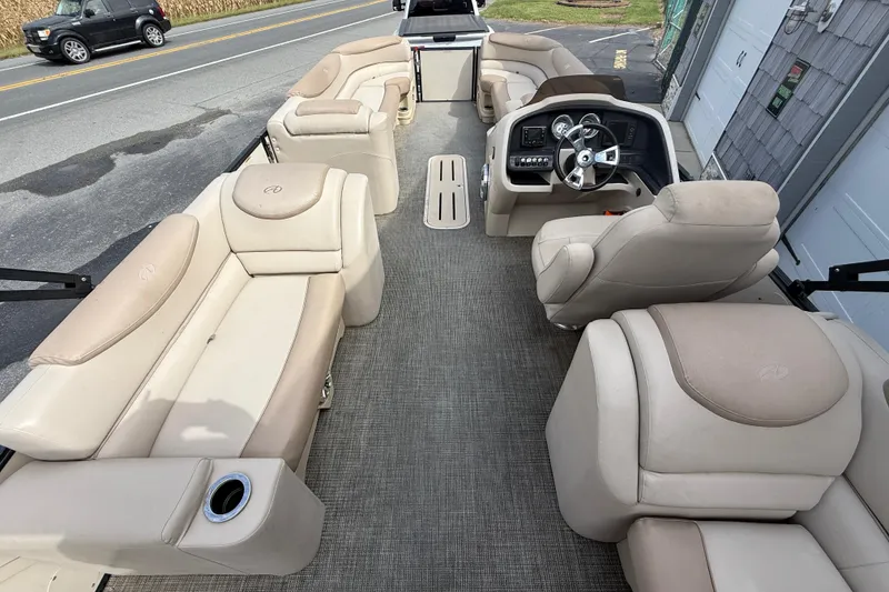 Slide: The Image of 2018 Avalon 2585 Catalina Elite Tri-toon boat interior with beige seating and steering console. - 24