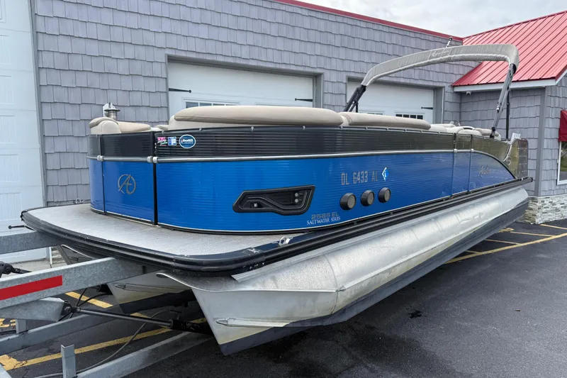 Slide: The Image of 2018 Avalon 2585 Catalina Elite Tri-toon boat on trailer, blue exterior, parked outside. - 3