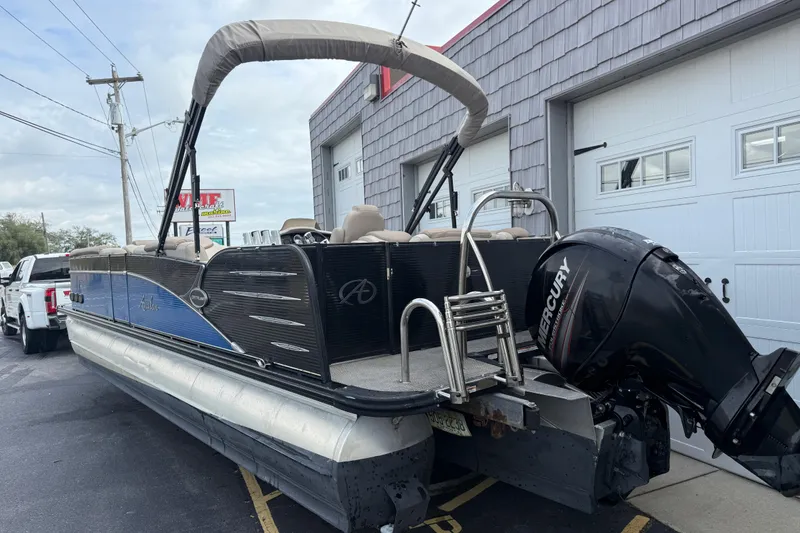 Slide: The Image of 2018 Avalon 2585 Catalina Elite Tri-toon boat with Mercury engine, parked outside a garage. - 7