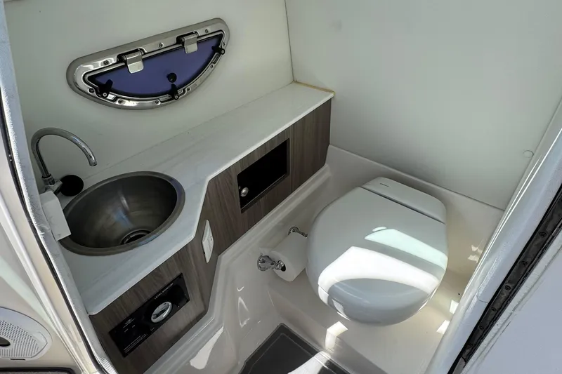 Slide: The Image of 2021 Regal 26 OBX boat bathroom with sink, toilet, and porthole window. - 20