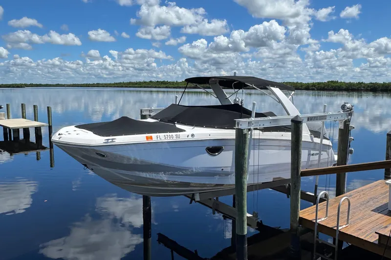 Slide: The Image of 2021 Regal 26 OBX boat docked on a serene lake under a cloudy sky. - 4