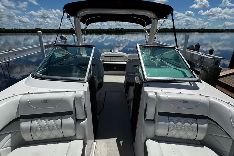 Slide: The Image of 2021 Regal 26 OBX boat interior with white seating, docked on a calm lake. - 9