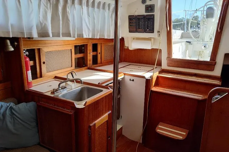 Slide: The Image of Interior of a 1979 Bristol Yawl sailboat with wooden cabinetry and a compact kitchen area. - 15