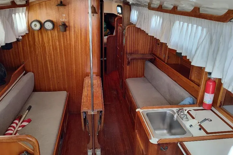 Slide: The Image of 1979 Bristol Yawl interior with wood paneling, seating, and kitchenette. - 16