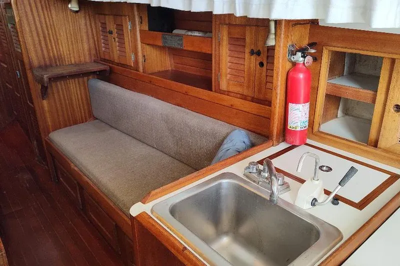 Slide: The Image of Interior of a 1979 Bristol Yawl sailboat with wooden cabinetry and a compact kitchen area. - 17