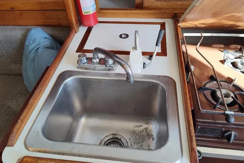 Slide: The Image of 1979 Bristol Yawl kitchen sink and stove with fire extinguisher. - 19