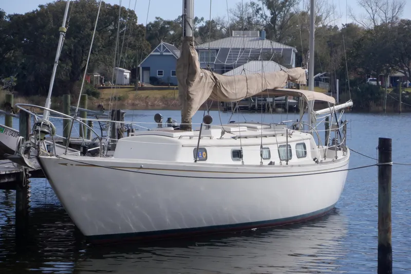 Slide: The Image of 1979 Bristol Yawl sailboat docked on a calm waterfront, surrounded by trees and buildings. - 2