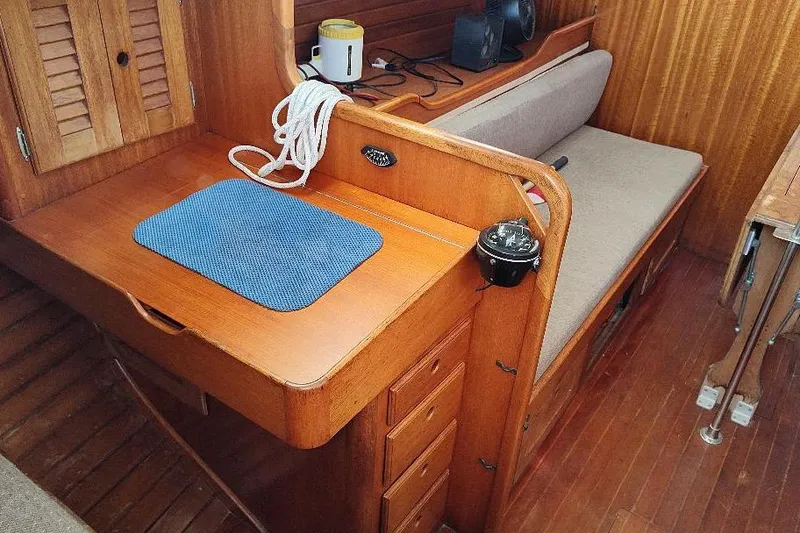 Slide: The Image of 1979 Bristol Yawl interior with wooden desk, blue mat, and beige seating. - 22