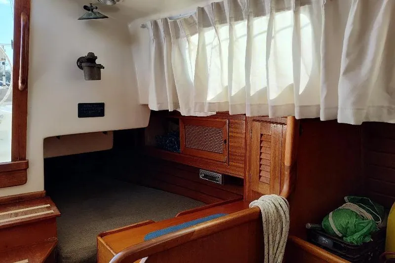 Slide: The Image of Interior of a 1979 Bristol Yawl sailboat with wooden furnishings and white curtains. - 28
