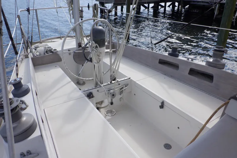 Slide: The Image of 1979 Bristol Yawl sailboat cockpit with steering wheel and rigging, docked by the water. - 5