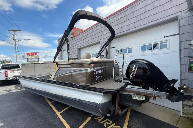 Slide: The Image of 2019 Avalon 2285 LSZ Cruise Tri-toon boat with Mercury engine parked outside a garage. - 6