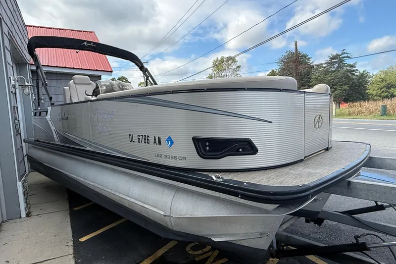 Slide: The Image of 2019 Avalon 2285 LSZ Cruise Tri-toon boat parked near a building under a cloudy sky. - 9