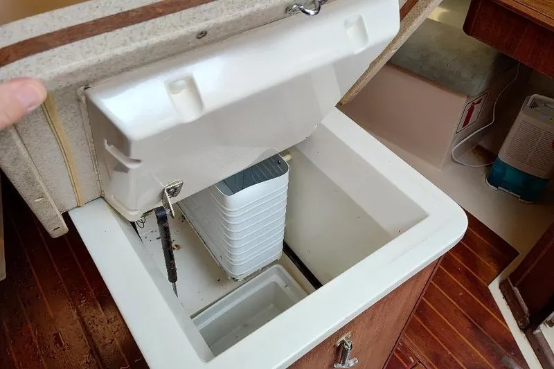 Slide: The Image of Open storage compartment inside 1989 Hunter Vision 32 sailboat, featuring wooden flooring and compact design. - 30