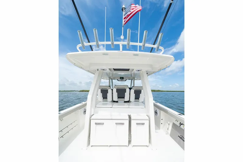 Slide: The Image of Manufacturer Provided Image: 2025 Pursuit S 358 Sport boat interior with seating and storage, American flag, ocean backdrop. - 14