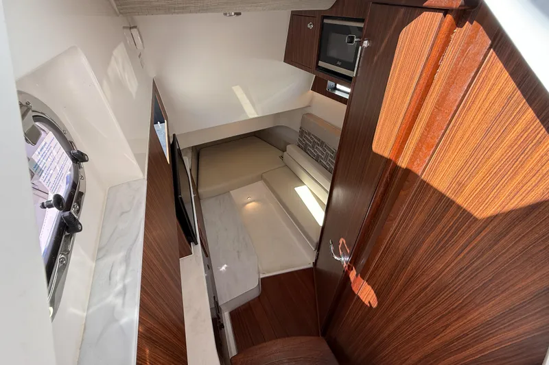 Slide: The Image of Interior of 2025 Pursuit S 358 Sport boat, featuring wood finishes and compact seating area. - 6