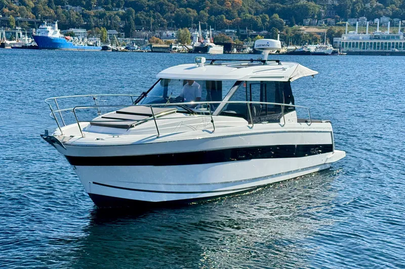 The Image of 2020 Jeanneau NC 895 boat cruising on a calm blue sea near a harbor. - 0