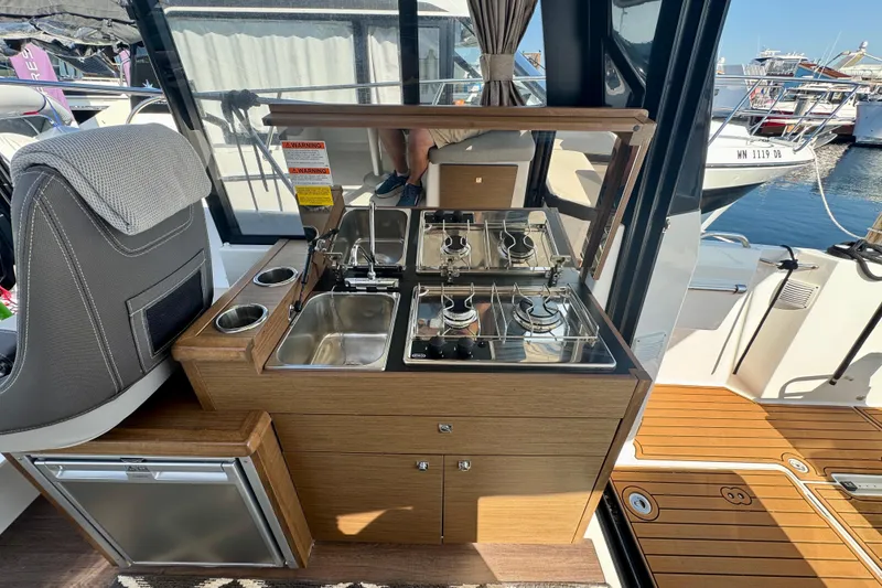 Slide: The Image of Compact kitchen area on a 2020 Jeanneau NC 895 boat, featuring stove, sink, and seating. - 18