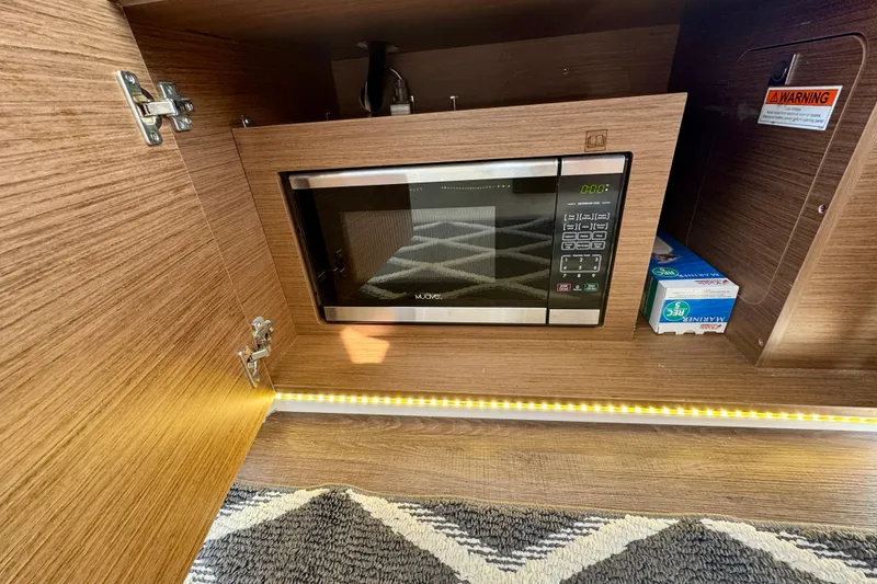 Slide: The Image of 2020 Jeanneau NC 895 interior with built-in microwave and wood cabinetry. - 19