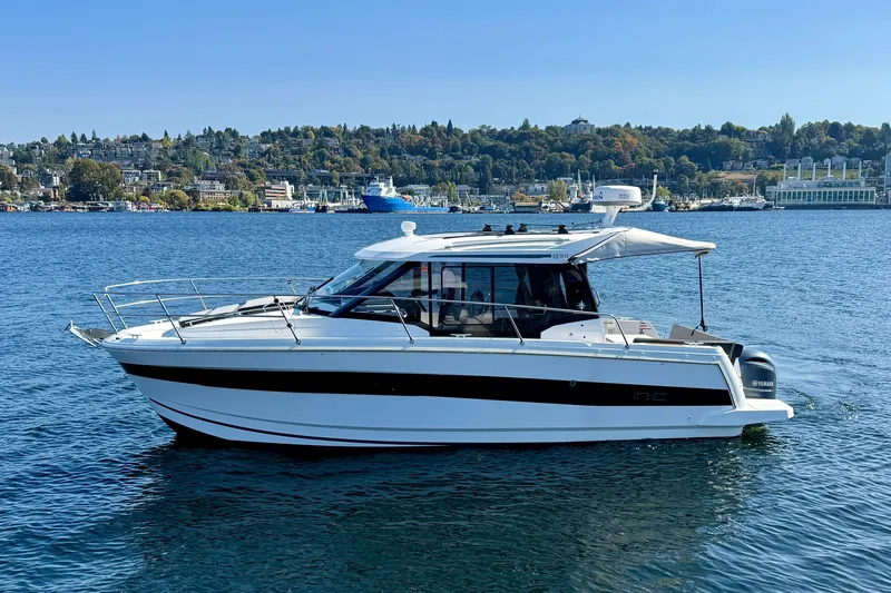 Slide: The Image of 2020 Jeanneau NC 895 boat on a scenic lake with cityscape background. - 2