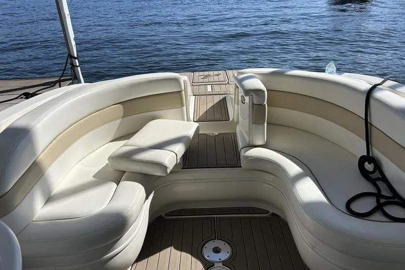 Slide: The Image of 2002 Sea Ray 290 Bowrider interior with white seating, docked by the water. - 6