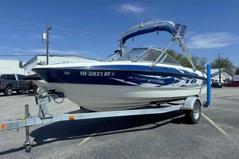 Slide: The Image of 2008 Bayliner Element F18 boat on trailer in parking lot, clear sky background. - 1