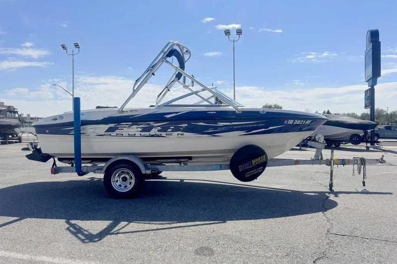 Slide: The Image of 2008 Bayliner Element F18 boat on trailer in parking lot under clear sky. - 2
