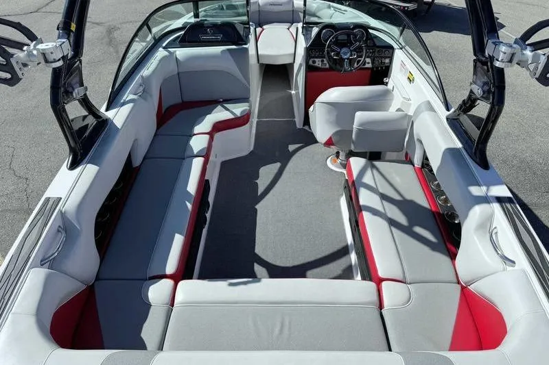 Slide: The Image of 2016 Moomba Mojo boat interior with gray and red seating, steering wheel, and dashboard. - 10