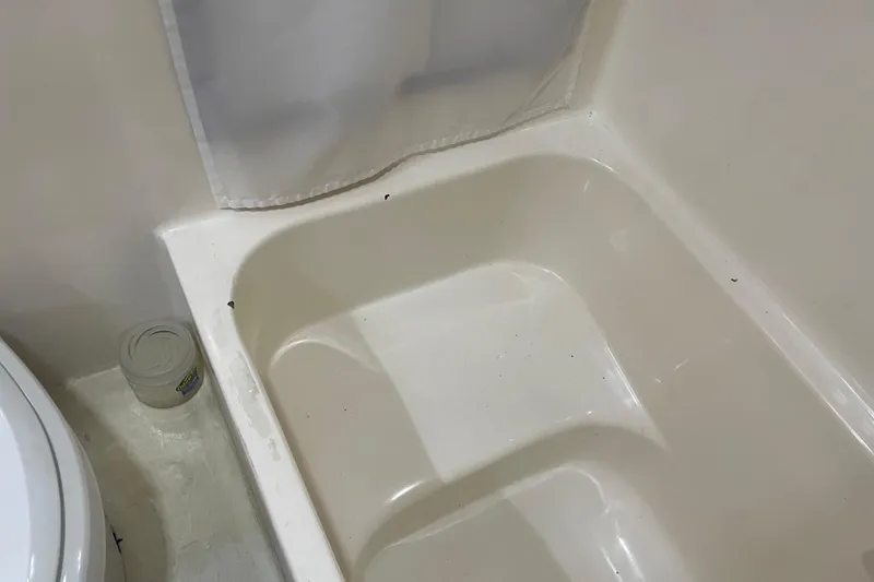 Slide: The Image of White bathtub interior with a shower curtain, adjacent to a toilet and a jar. - 46